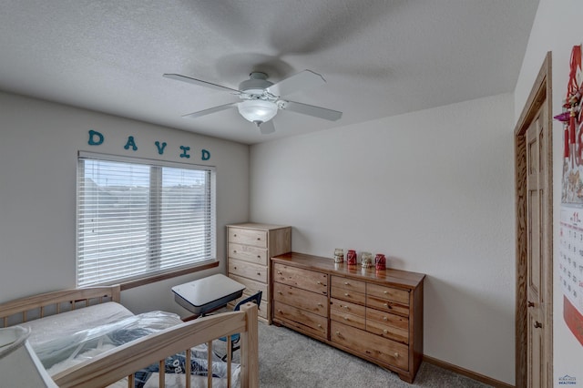 carpeted bedroom featuring ceiling fan and a textured ceiling