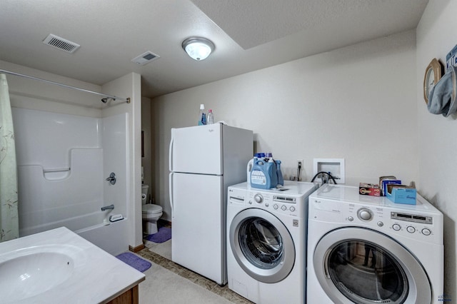 laundry area with washer and clothes dryer, a textured ceiling, and sink