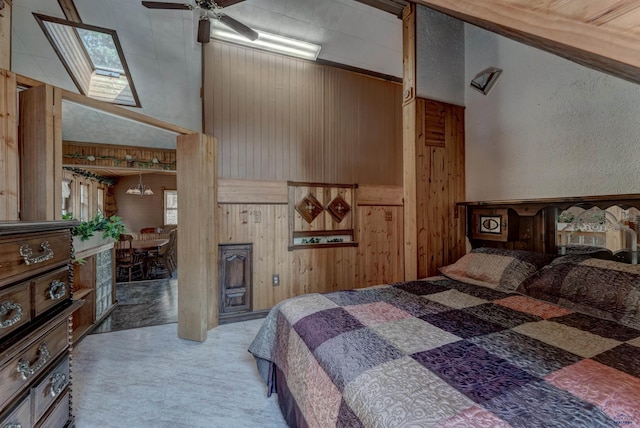 bedroom with carpet floors, ceiling fan, wooden walls, and vaulted ceiling with skylight