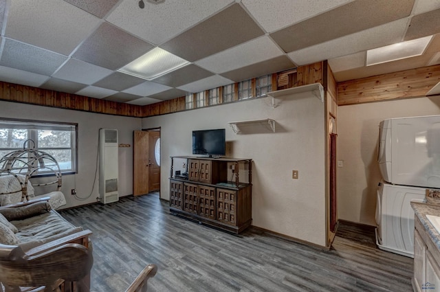 living room with a paneled ceiling, hardwood / wood-style floors, and stacked washing maching and dryer