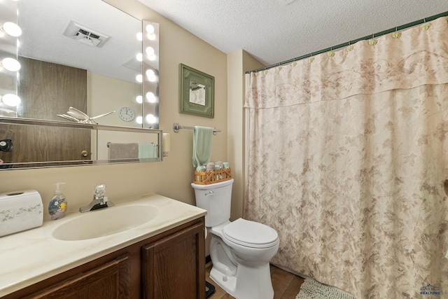 bathroom with vanity, toilet, and a textured ceiling