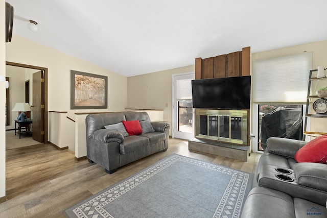 living room featuring a fireplace, light wood-type flooring, a wealth of natural light, and lofted ceiling