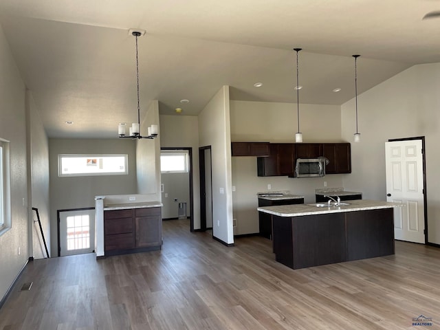 kitchen with a chandelier, wood-type flooring, dark brown cabinetry, and a healthy amount of sunlight