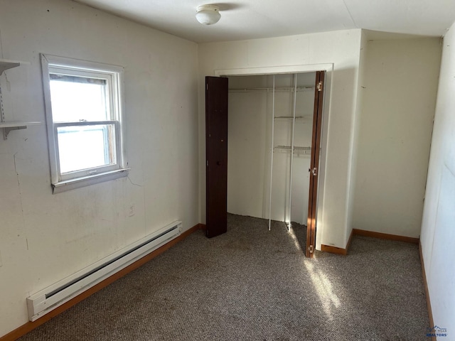 unfurnished bedroom with dark colored carpet, a closet, and baseboard heating