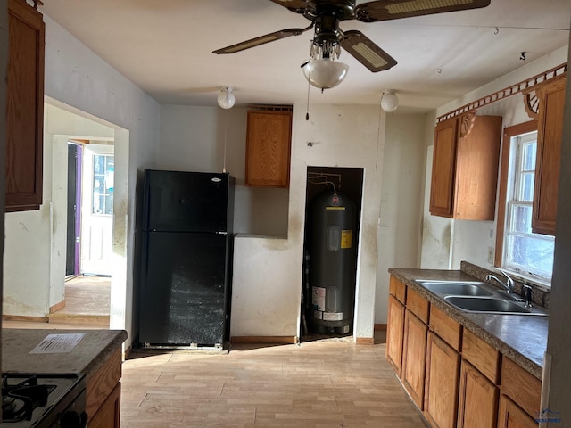 kitchen with ceiling fan, sink, black fridge, light hardwood / wood-style flooring, and water heater