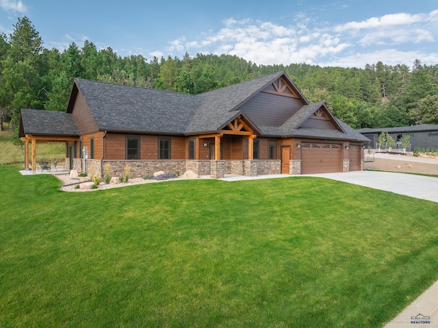 view of front of house featuring roof with shingles, an attached garage, stone siding, driveway, and a front lawn