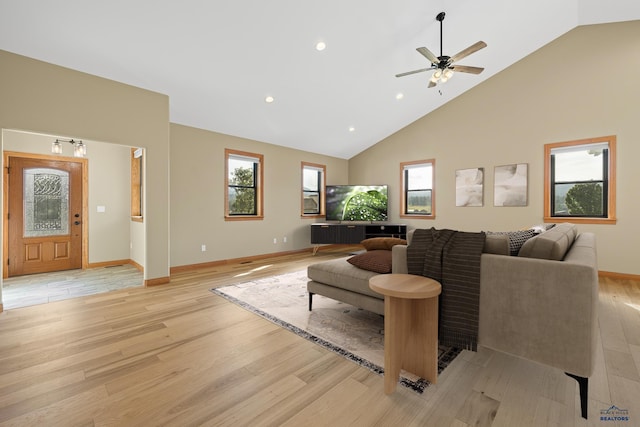 living area featuring high vaulted ceiling, light wood-style flooring, and baseboards