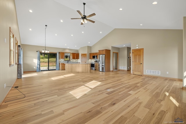 unfurnished living room featuring ceiling fan with notable chandelier, high vaulted ceiling, light wood finished floors, and visible vents