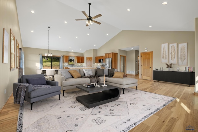 living area featuring light wood finished floors, recessed lighting, visible vents, high vaulted ceiling, and ceiling fan with notable chandelier