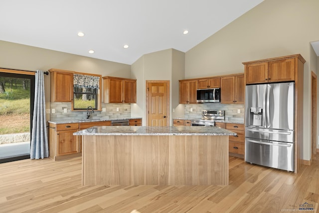 kitchen featuring stainless steel appliances, a center island, brown cabinets, and a sink