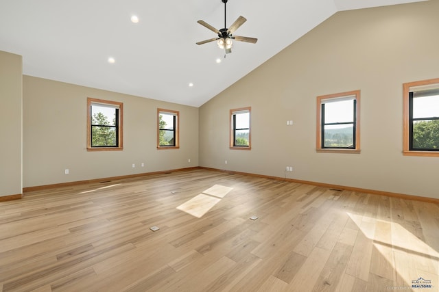 spare room with baseboards, high vaulted ceiling, plenty of natural light, and light wood-style floors