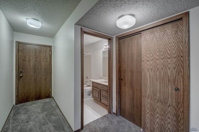 hall featuring sink, light colored carpet, and a textured ceiling