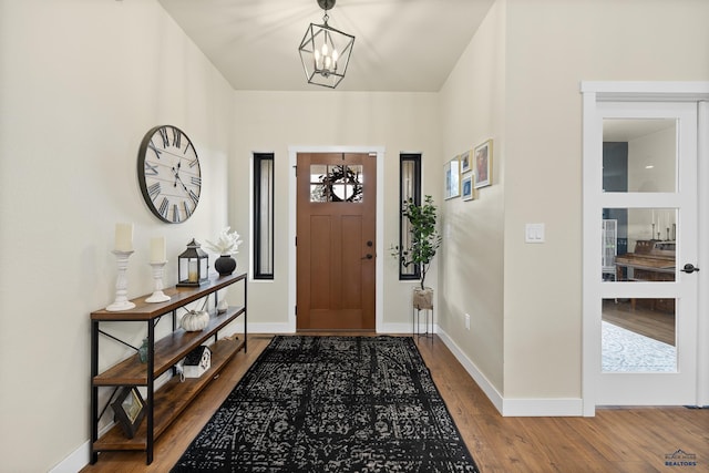 foyer entrance with hardwood / wood-style floors and an inviting chandelier