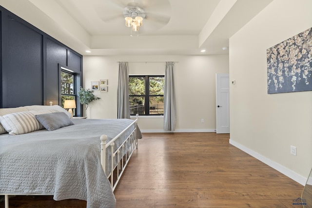 bedroom with a tray ceiling, ceiling fan, and dark hardwood / wood-style floors