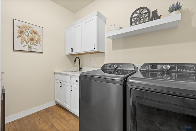 washroom featuring washing machine and clothes dryer, light wood-type flooring, cabinets, and sink