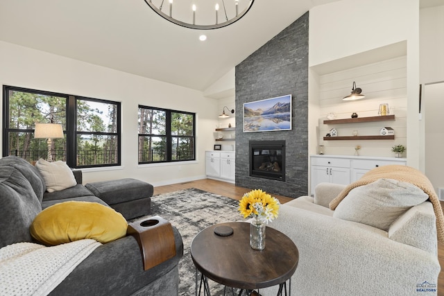 living room with light hardwood / wood-style floors, a fireplace, high vaulted ceiling, and an inviting chandelier