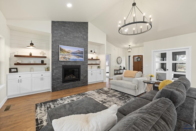 living room with a fireplace, an inviting chandelier, light hardwood / wood-style flooring, and lofted ceiling