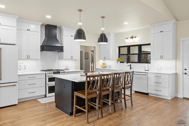 kitchen with custom exhaust hood, white appliances, white cabinets, a kitchen breakfast bar, and a kitchen island