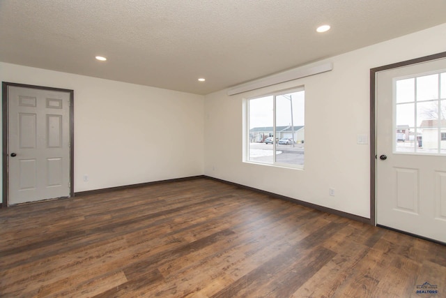 empty room featuring dark wood-type flooring and a textured ceiling