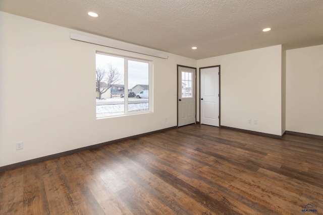 empty room featuring dark hardwood / wood-style flooring, a textured ceiling, and plenty of natural light