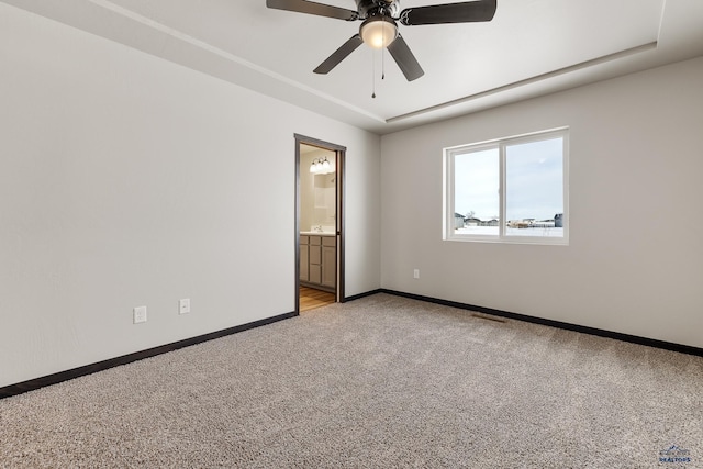 carpeted empty room featuring a tray ceiling and ceiling fan