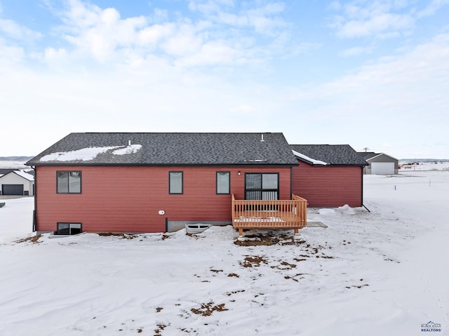 snow covered back of property featuring a deck