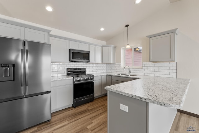 kitchen featuring gray cabinetry, sink, light hardwood / wood-style floors, vaulted ceiling, and appliances with stainless steel finishes