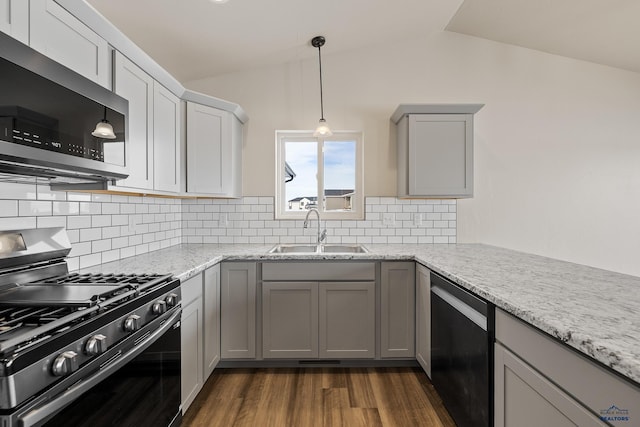 kitchen with sink, vaulted ceiling, gray cabinets, light stone counters, and stainless steel appliances