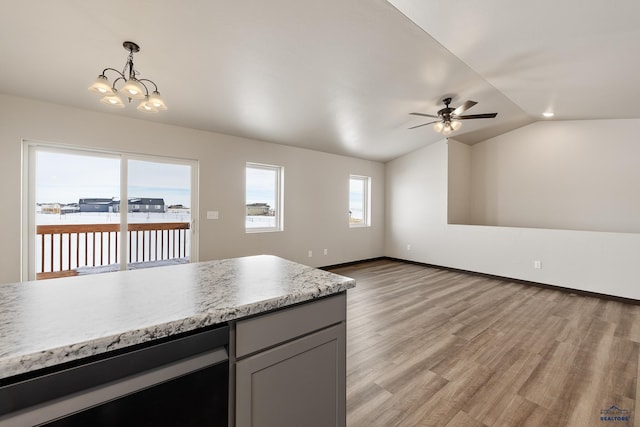 kitchen with gray cabinetry, light hardwood / wood-style flooring, vaulted ceiling, decorative light fixtures, and ceiling fan with notable chandelier