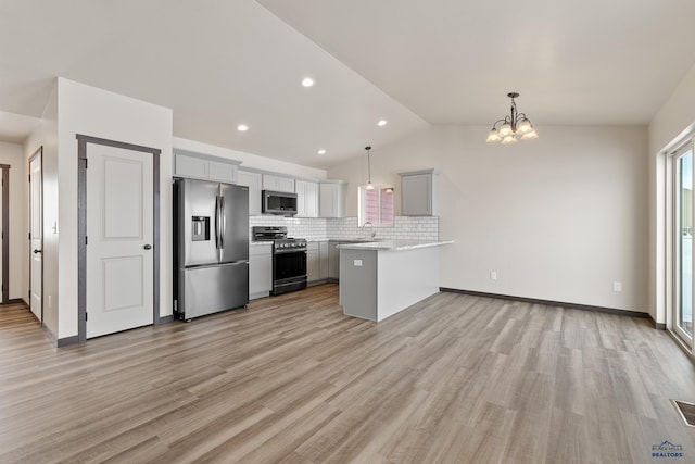 kitchen featuring backsplash, stainless steel appliances, pendant lighting, a notable chandelier, and lofted ceiling