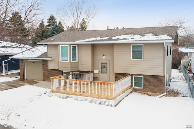 snow covered back of property featuring a garage