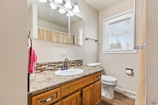 bathroom featuring decorative backsplash, vanity, hardwood / wood-style flooring, and toilet