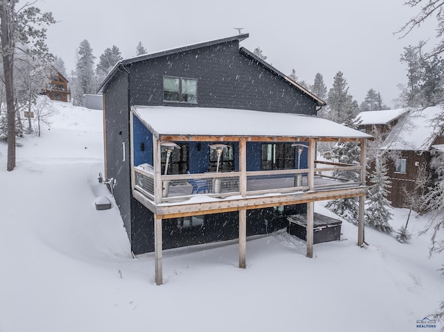 snow covered back of property featuring a wooden deck