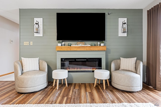 living area featuring hardwood / wood-style flooring, a fireplace, and wooden walls