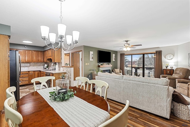 dining space with dark hardwood / wood-style flooring, sink, and ceiling fan with notable chandelier