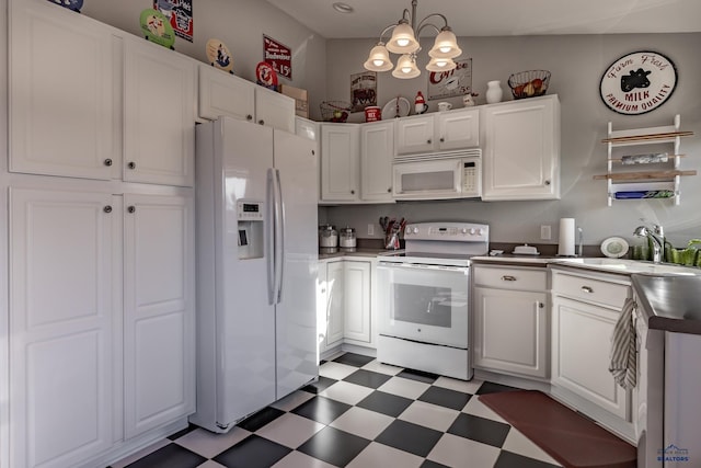 kitchen featuring sink, white appliances, white cabinetry, hanging light fixtures, and a notable chandelier