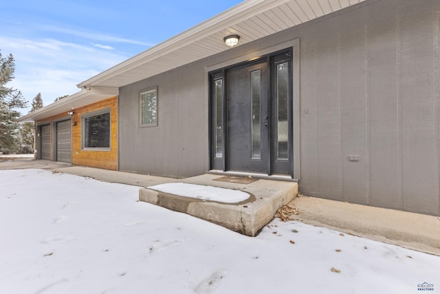 snow covered property entrance with a garage