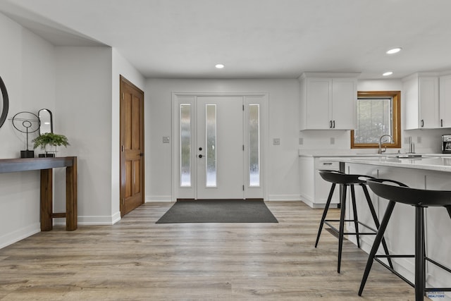 kitchen with a kitchen breakfast bar, dishwasher, white cabinetry, and light hardwood / wood-style floors