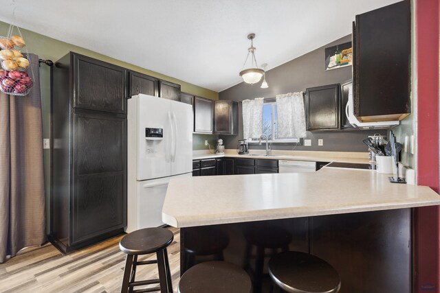 kitchen with lofted ceiling, white appliances, kitchen peninsula, a breakfast bar area, and pendant lighting