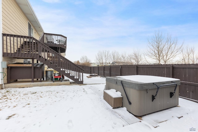 snowy yard with a hot tub and a wooden deck