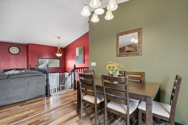 dining area with lofted ceiling, hardwood / wood-style floors, and a notable chandelier