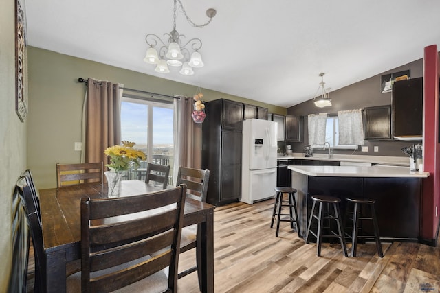 dining space featuring a notable chandelier, a healthy amount of sunlight, vaulted ceiling, and light wood-type flooring