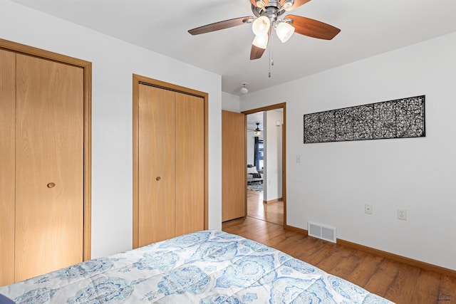 bedroom with multiple closets, ceiling fan, and light hardwood / wood-style floors