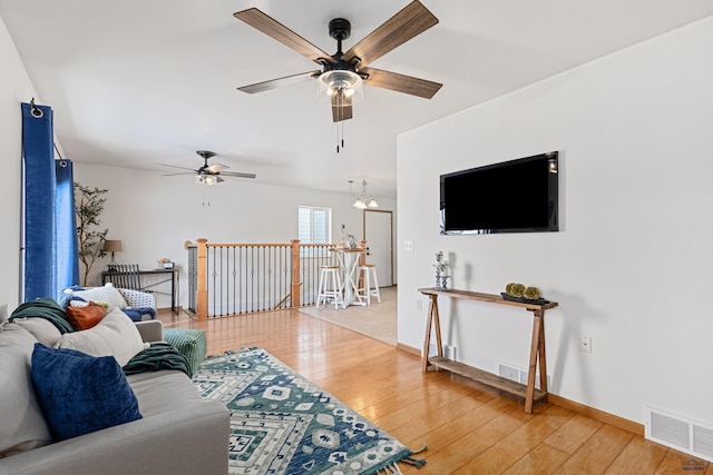 living room featuring ceiling fan with notable chandelier and hardwood / wood-style flooring