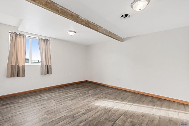 empty room featuring hardwood / wood-style floors and beamed ceiling