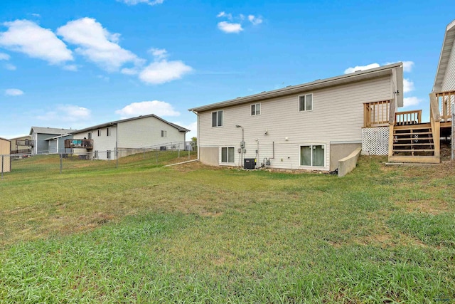 back of property with a lawn, central AC unit, and a wooden deck