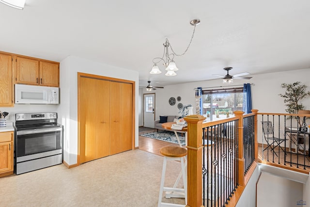 kitchen with decorative light fixtures, light colored carpet, stainless steel electric range, and ceiling fan with notable chandelier