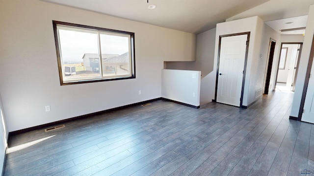 spare room featuring vaulted ceiling and dark hardwood / wood-style floors