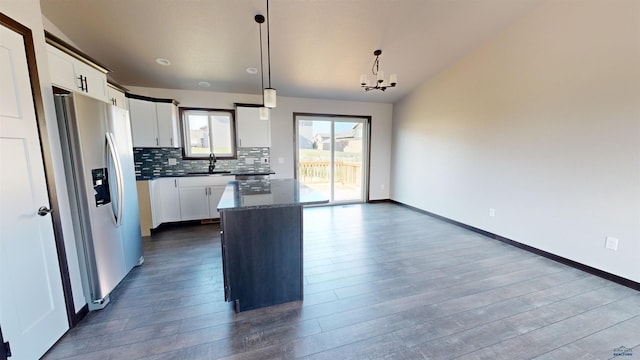 kitchen with stainless steel fridge, white cabinetry, decorative light fixtures, and a center island