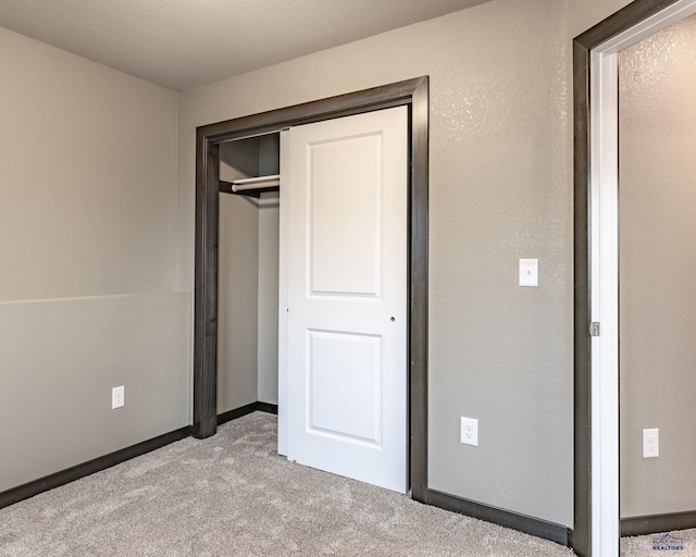 unfurnished bedroom featuring a closet and light colored carpet